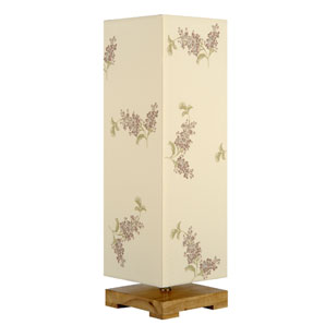 Short, square wooden base, topped with a cream column shade decorated with clusters of lilac