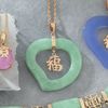 Carved jade heart pendant with a 9ct gold chain and Chinese luck symbol.