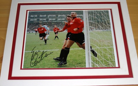 Old Trafford legend Eric Cantona has signed this superb photo in black pen.  The photograph has