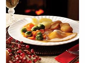 Sliced roast turkey in gravy with roast and boiled potatoes, brussel sprouts and carrots.