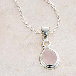 Gently curving lines in sterling silver encircle a delicate stone of rose quartz